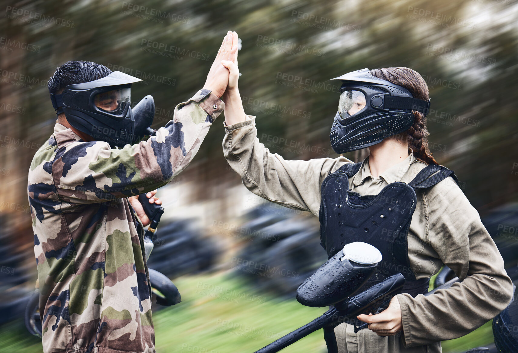 Buy stock photo Paintball, team and high five for winning victory, achievement or successful game time on the field. Man and woman in celebration for war win in extreme sports together and touching hands in teamwork