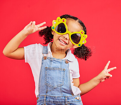 Buy stock photo Funny, sunglasses and girl playful, peace and happiness with young person on red studio background. Portrait, mockup and female child with silly eyewear, fun and creative on break, smile and stylish