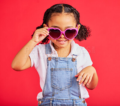 Buy stock photo Little girl, fashion and heart sunglasses on isolated red background in children trend, holiday style or cool summer. Smile, happy and kid with glasses for eyes healthcare, wellness or sun protection