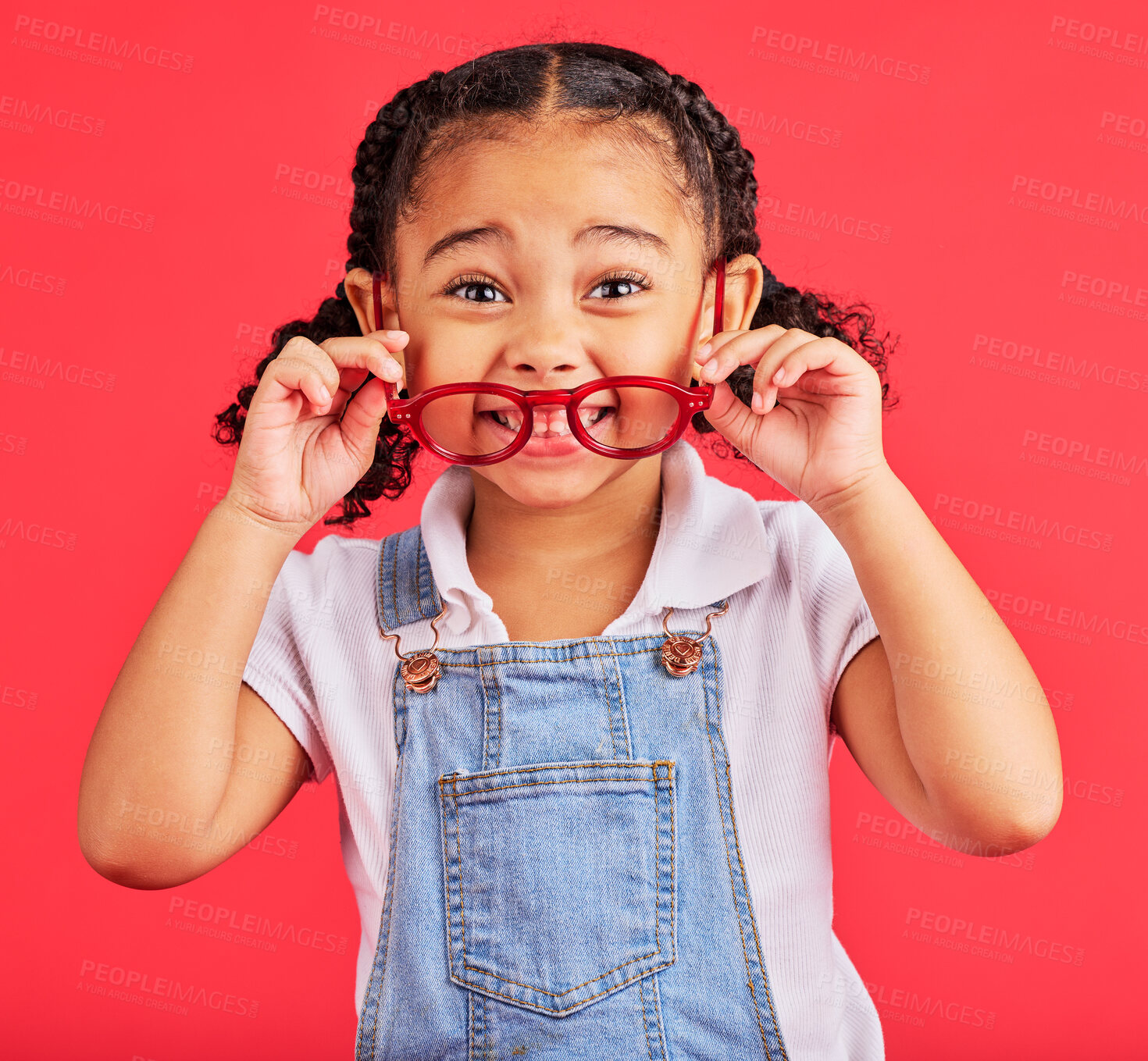 Buy stock photo Eyes, glasses in hands and portrait of child with cute smile and isolated on red background. Vision, eyesight and happy playful expression, goofy little girl holding spectacles for eyesight in studio