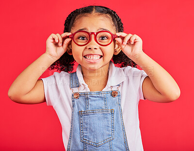 Buy stock photo Excited child, portrait or fashion glasses on red background in children trend, eyes care or wellness health. Smile, happy or little girl with optometry frames for vision support or medical insurance