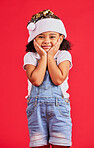 Little girl, face and portrait smile for Christmas, celebration or surprise isolated on a red studio background. Happy child smiling in happiness with hands looking adorable for festive season gift