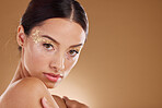 Gold makeup, woman and beauty portrait with model ready for cosmetic, wellness and spa. Brown background, studio and isolated young female person with mock up, cosmetics and glitter eyes alone 
