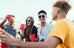 Group of friends, drinks and a party outdoor to celebrate at  festival, celebration or summer social event. Diversity young men and women people together while talking, happy and drinking alcohol
