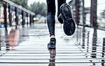 Runner training in the rain, person doing workout and outdoor cardio for marathon race in Seattle road. Shoes splash water in puddle, step on wet ground and legs moving fast for fitness exercise