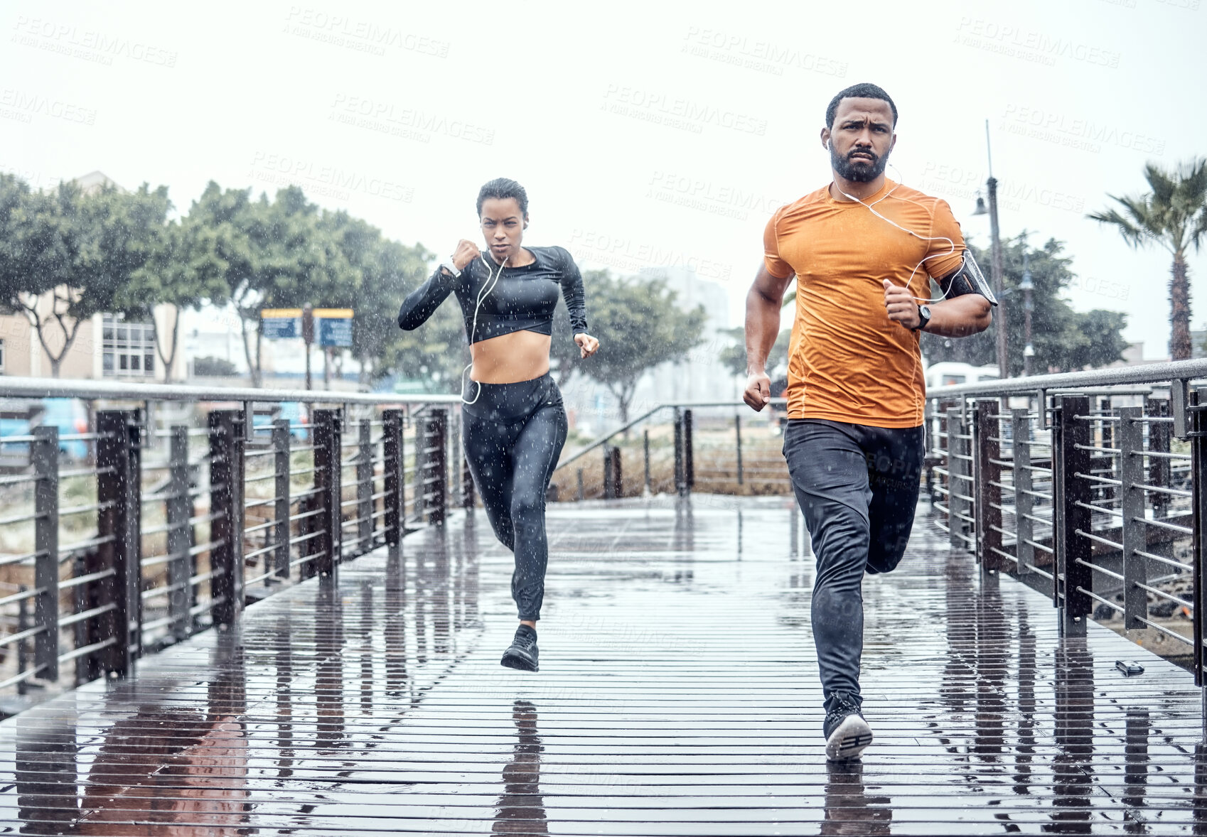 Buy stock photo Personal trainer, rain and athletes running as exercise on a city bridge training, fitness or workout outdoors in town. People or fit friends sprint fast for wellness, cardio and health lifestyle