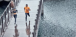Overhead, fitness and man with woman running as exercise on city promenade training or workout outdoors in a town. Athlete, runner and fit male sprint fast for wellness, cardio and health by water