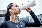 Fitness, water and black woman drinking in city for wellness, healthy body and cardio workout outdoors. Sports, motivation and girl listening to music for exercise, running and marathon training