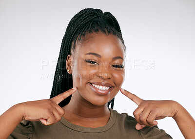Buy stock photo Portrait, teeth and a black woman pointing to her mouth in studio on a gray background for oral hygiene. Face, dental and an attractive young female inside to point at her cheek for tooth whitening