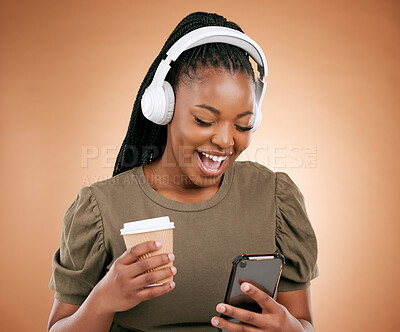 Buy stock photo Mobile, music and coffee with a black woman in studio on a beige background listening to the radio. Phone, social media or headphones and a young female streaming an audio playlist with a drink