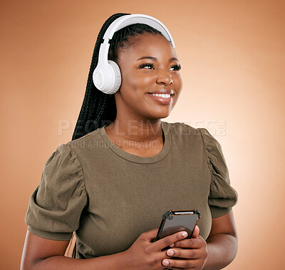Buy stock photo Black woman, phone and headphones with smile for music or entertainment against a studio background. Happy African American female smiling in joyful happiness listening or streaming audio track