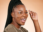 Black woman, face and holding glasses for fashion, style or smart casual against a studio background. Portrait of happy African American female model smile for eyewear, spectacles and sight or vision