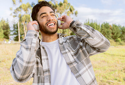 Buy stock photo Happy, man and music with headphones in forest, laugh and relax on blue sky, tree and space background. Radio, earphones and guy, smile and joy while listening to audio, podcast or track in nature