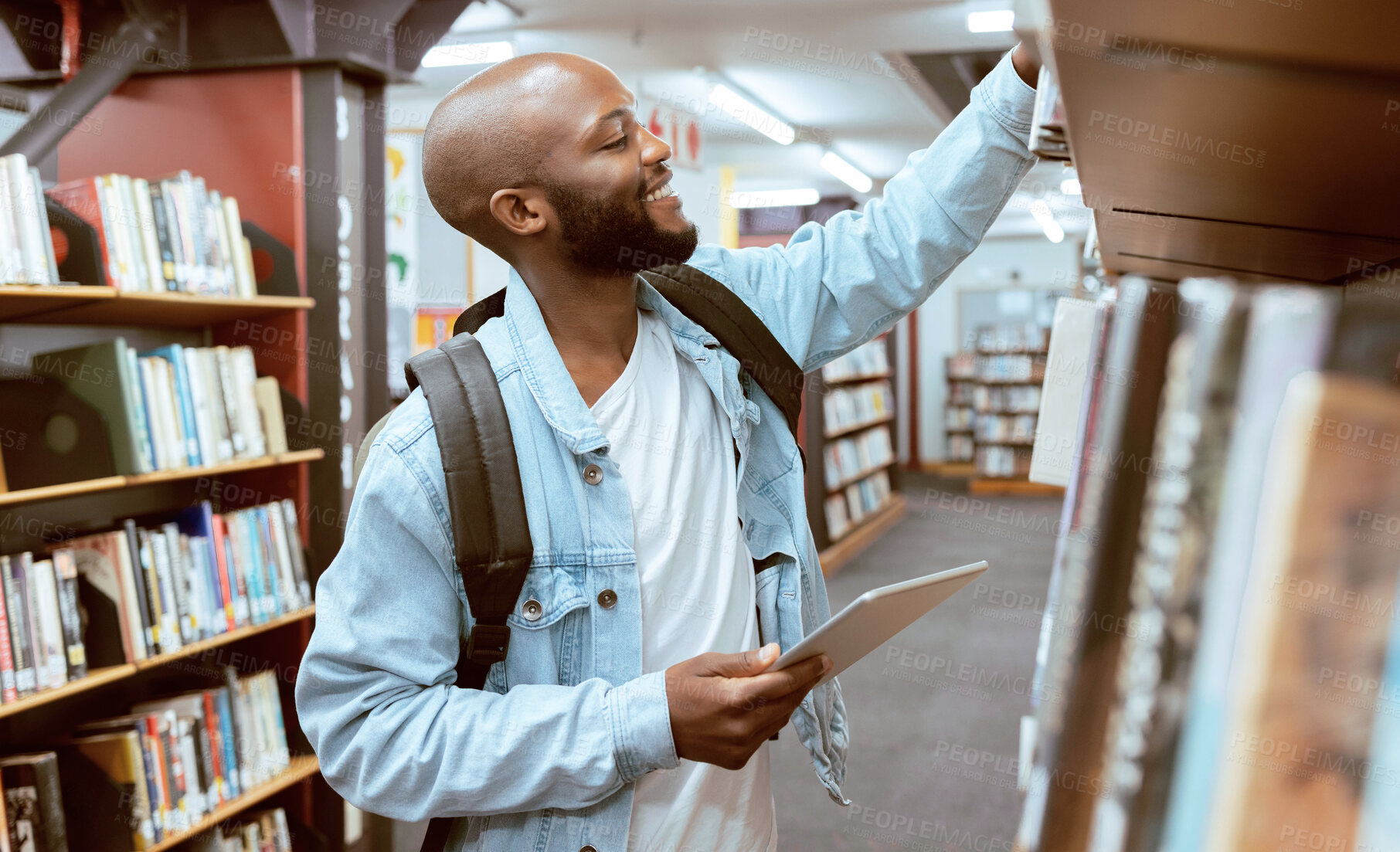 Buy stock photo Black man, student and library bookshelf  of a university, college and knowledge center. Notebook, happy young person and smile of a male with books for learning and study research info at school 