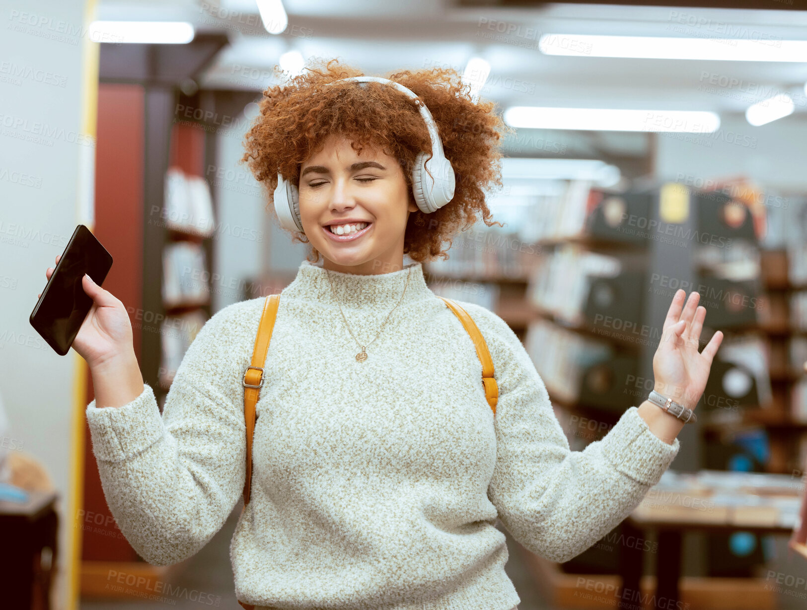 Buy stock photo Music, dance and headphones with a student black woman listening to the radio in a university library. Phone, internet and a young female college pupil streaming audio while dancing or having fun