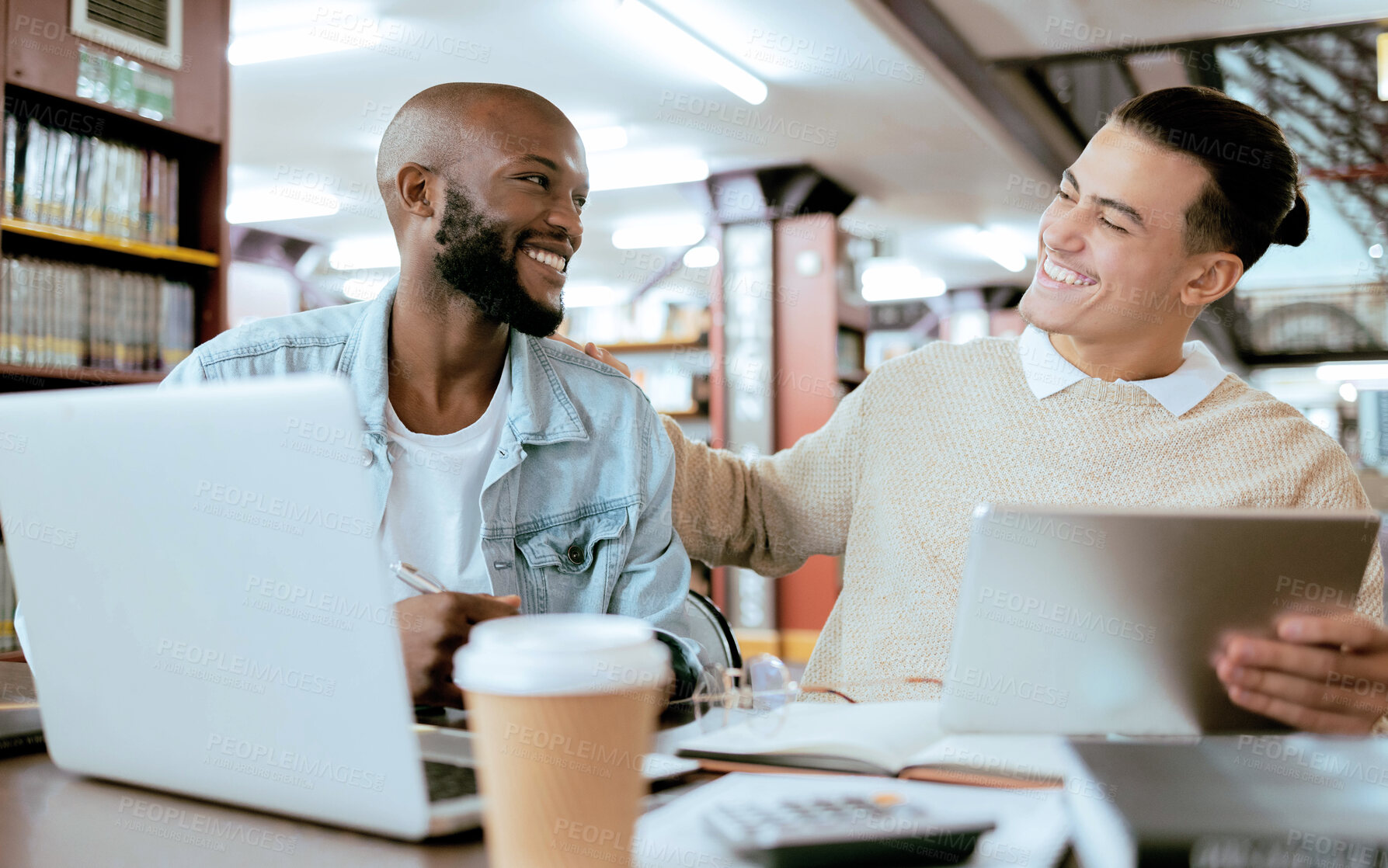 Buy stock photo Students, men and library with study support at desk with laptop, tablet and happy for learning opportunity. Student friends, laugh together and vision for university success, diversity and teamwork