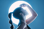 Beauty, light and profile of a model in a studio with a sensual, soft and attractive pose. Cosmetic, magical and slim woman with a mystical glow posing by a moon while isolated by a blue background.