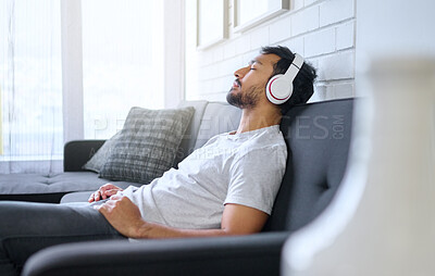 Buy stock photo Music, relax and man with headphones on sofa in home living room streaming radio or podcast. Meditation, technology and male on couch in lounge listening to peaceful song, audio or album in house.