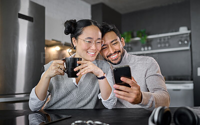 Buy stock photo Love, coffee and couple with phone in home kitchen watching video online. Social media, tea and diversity of man and woman with mobile smartphone streaming movie or film and bonding at night in house