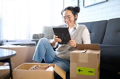 Buy stock photo Tablet, real estate and Asian woman moving into new home while planning or calculating mortgage online. Relocation boxes, technology and female property owner or remote worker in living room of house
