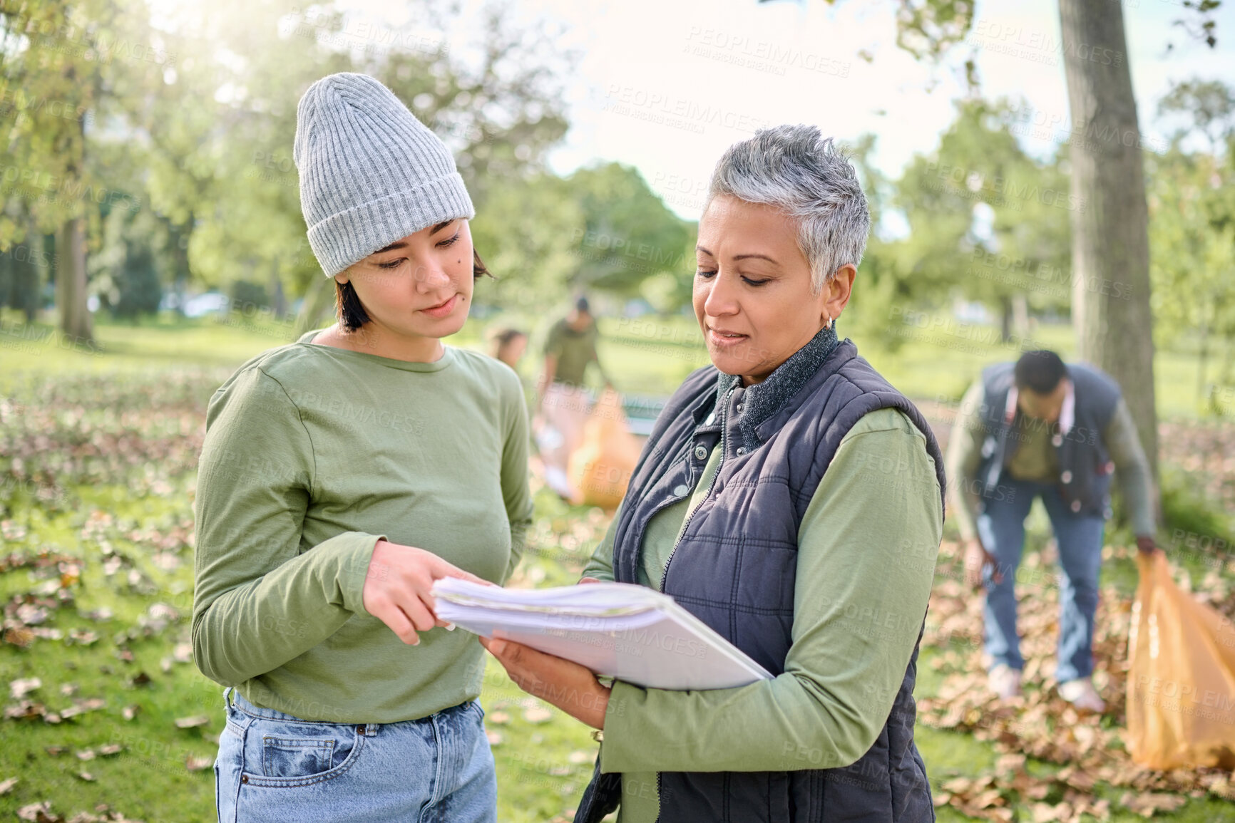 Buy stock photo Volunteer schedule, community cleaning and charity work outdoor with women planning a project. Recycle team, collaboration and eco friendly job with people checking volunteering data in a park