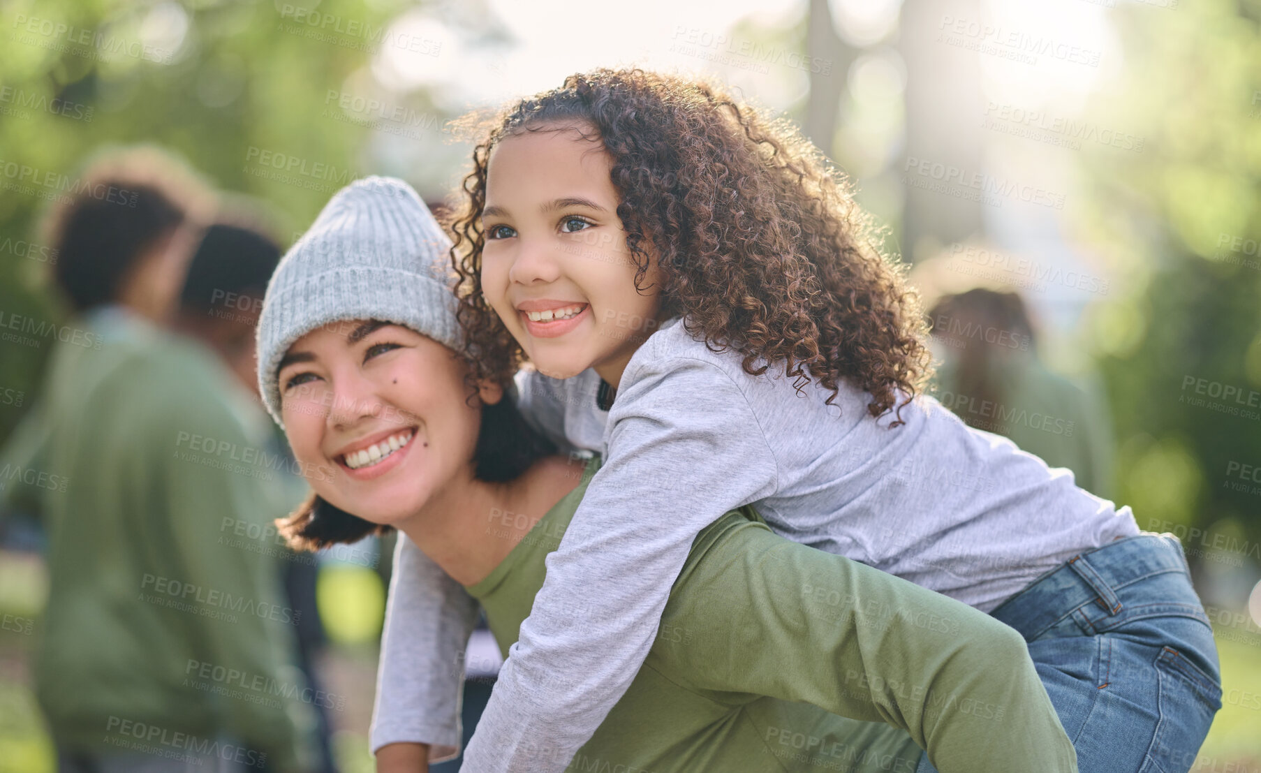 Buy stock photo Mother smile, piggy back hug and interracial family with girl and mom together in nature. Park, happy summer and mama with love and care for child playing outdoor in a garden with blurred background