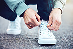 Road, hands and man tie shoes on street to start fitness walk on holiday or vacation outdoors. Travel, wellness and male traveller tying footwear laces and getting ready for walking, journey or trek.