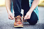 Hands, road and man tie shoes on street to start fitness walk on holiday or vacation outdoors. Travel, wellness and male traveller tying footwear laces and getting ready for walking, journey or trek.