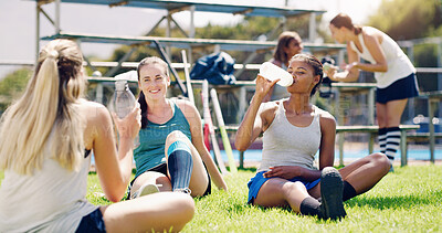 Buy stock photo Sport, outdoor and women relax with water bottle, hydration and rest, field hockey athlete take training break. Health, wellness and fitness with sports team, collaboration and drink after workout