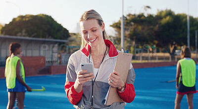 Buy stock photo Hockey, coach and woman with phone at group training at a stadium for fitness, match and game. Sports, trainer and female laughing at meme, text or online message during morning cardio with players