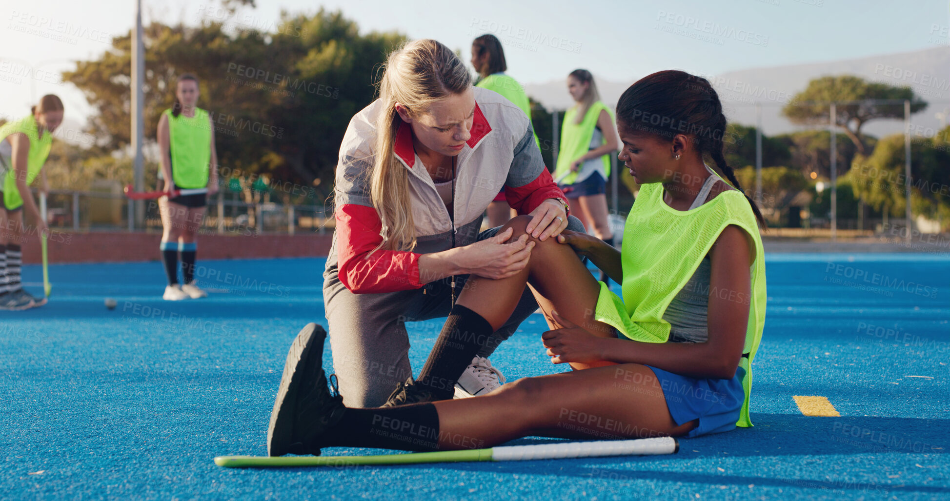 Buy stock photo Woman, sports and knee injury in hockey training, practice or game on a blue turf with coach and team. Sport mentor helping female in leg pain, accident or bruise from physical activity during match