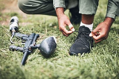 Buy stock photo Paintball, gun and shooter or man kneeling ready for competitive match or competition in the forest. Player, athlete and person tying laces with game equipment or weapon on a sports field 