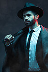 Fashion, criminal and man with bat for violence for vintage, retro and Victorian gangster on dark background. Crime aesthetic, thinking and male model with designer suit, weapon and threatening face