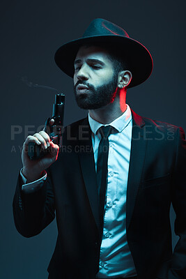 Buy stock photo Man, suit or blowing gun barrel on dark studio background in secret spy, isolated mafia leadership or crime lord safety. Model, gangster or hitman pistol in style, formal or fashion clothes aesthetic