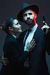 Couple, fashion or gun on dark studio background in secret spy, isolated mafia safety or crime lord security. Gangster love, woman or model with weapon in stylish, trendy or fashion clothes aesthetic