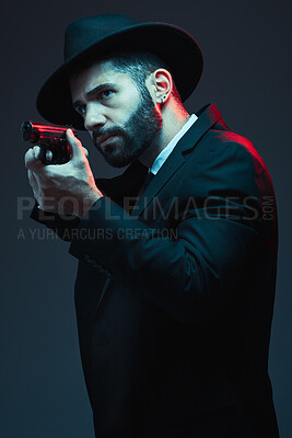 Buy stock photo Gangster, suit and shooting gun on dark studio background in secret spy, isolated mafia leadership and crime lord security. Model, man and hitman aiming weapon in formal or fashion clothes aesthetic
