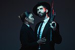 Couple, fashion or weapon on dark studio background in secret spy, isolated mafia safety or crime lord security. Gangster love, woman or model with gun in stylish, trendy or fashion clothes aesthetic