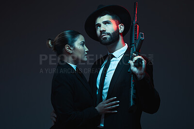 Buy stock photo Couple, fashion or weapon on dark studio background in secret spy, isolated mafia safety or crime lord security. Gangster love, woman or model with gun in stylish, trendy or fashion clothes aesthetic
