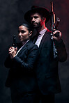 Gangster couple, fashion or gun on studio background in secret spy, isolated mafia safety or crime lord security. Man, love or model woman with pistol in stylish, trendy or fashion clothes aesthetic
