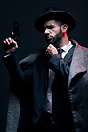 Gangster, leadership or holding gun on studio background in dark secret spy, isolated mafia or crime lord security. Model, man and hitman suit with weapon in formal style or fashion clothes aesthetic