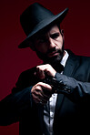 Gangster, suit or cocking gun on studio background in dark secret spy, isolated mafia leadership or crime safety. Model, assassin or hitman weapon in ready, formal style or fashion clothes aesthetic