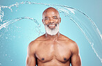 Senior, water splash and portrait of a black man in studio shower for skincare and beauty. Smile, blue background and isolated elderly person with happiness for body cleaning and morning dermatology