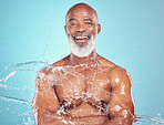 Portrait, skincare and senior man in studio for beauty, grooming and water splash on blue background. Elderly, model and guy relax while cleaning, hygiene and skin wellness, hydration and isolated