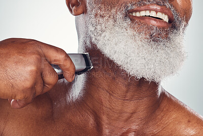 Buy stock photo Hand, beard and shaving with an electric razor with a mature black man in studio on a gray background. Face, grooming and hygiene with a mature male in the bathroom to shave for hair removal