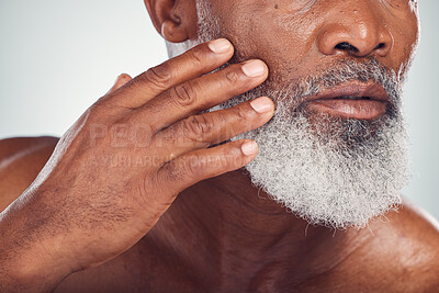 Buy stock photo Hand, beard and face with a senior black man grooming in studio on a gray background for beauty or skincare. Skin, hygiene and cosmetics with a mature male indoor to promote facial hair maintenance