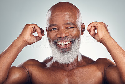 Buy stock photo Portrait of black man cleaning ear with smile, body care and grooming isolated on grey background. Morning routine, health and happy senior male with earbuds in ears to clean for wellness in studio.