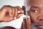 Grooming, zoom and black man with a tweezers for hair removal isolated on a studio background. Cleaning, beauty and face of an African senior model with a tool for facial care on a grey backdrop