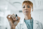 Science research, planning or elderly woman scientist writing on glass board, strategy working in laboratory for future medicine and innovation. Worker, doctor or employee thinking of futuristic idea