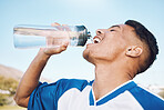 Water, bottle and football or soccer player on sports field resting after match or competition on a sunny day. Man, athlete and sportsman refreshing during a game happy and smiling for due to fitness