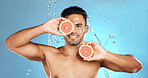 Man, portrait smile and fruit for skincare, healthy nutrition or vitamin C and hydration against a blue studio background. Happy male holding grapefruit for natural organic diet or body wellness